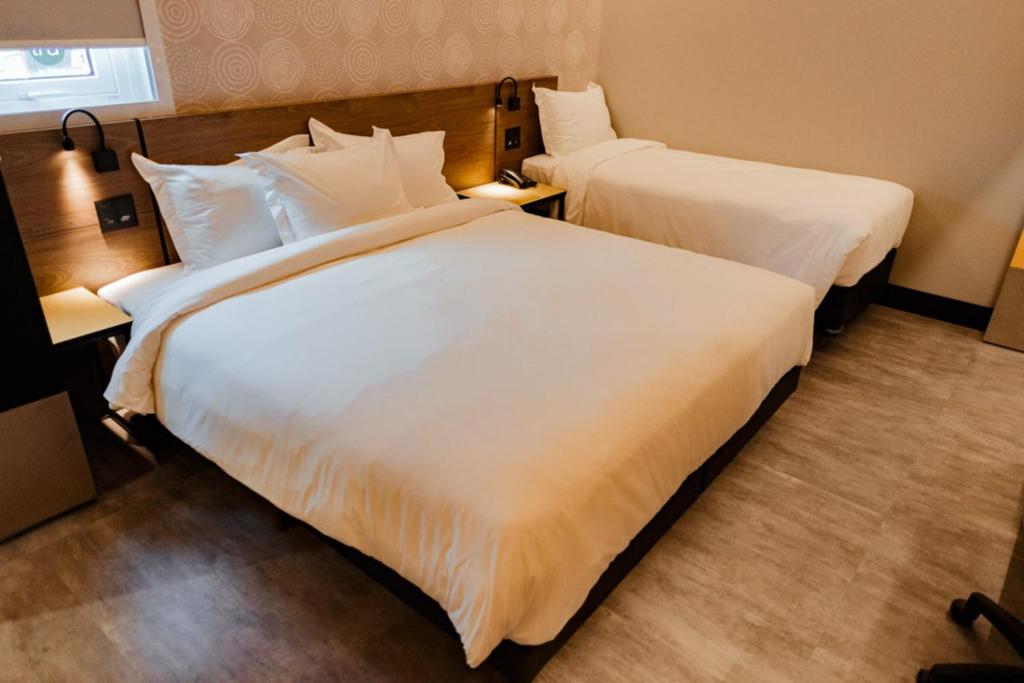 two beds in a hotel room with white sheets at Tru By Hilton Criciúma in Criciúma