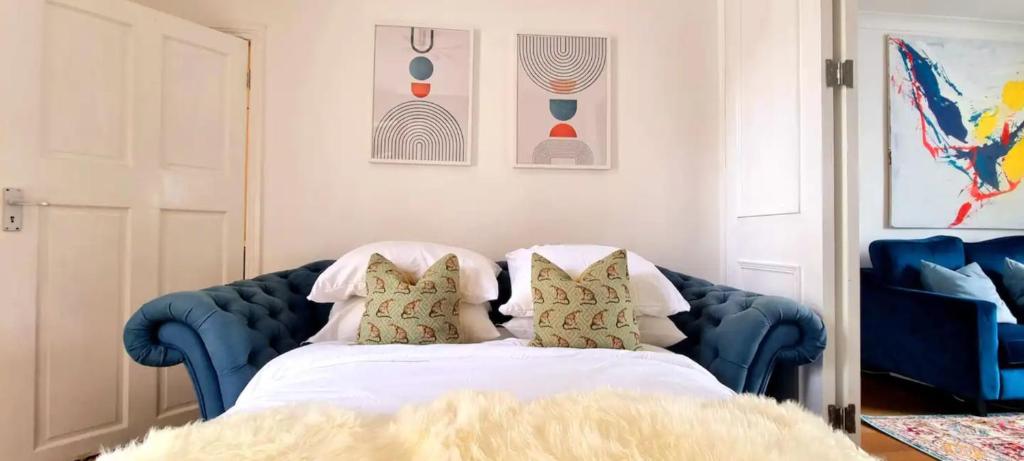 a bedroom with a blue bed with pillows at Stylish 3 Bedroom Townhouse in Brockley with Large Garden in London