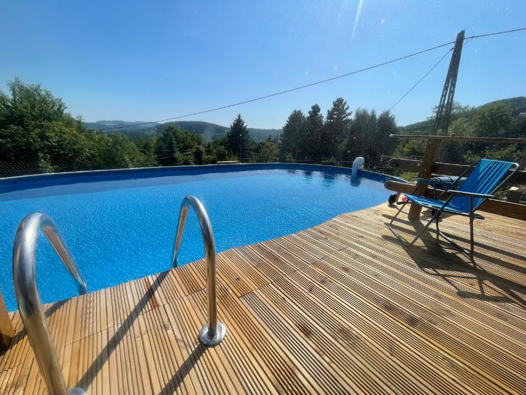 a deck with a blue chair next to a swimming pool at apartamentwroznowiepl in Rożnów