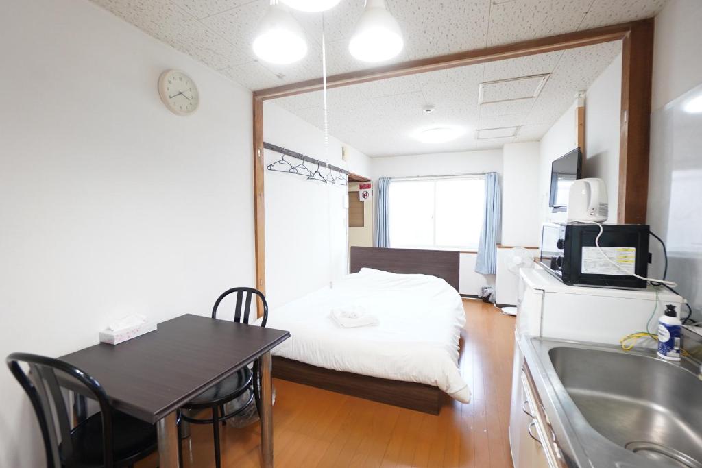 Cette petite chambre comprend un lit, une table et une cuisine. dans l'établissement NEAR Sapporo St & Hokkaido University Cozy studio sanwa101, à Sapporo