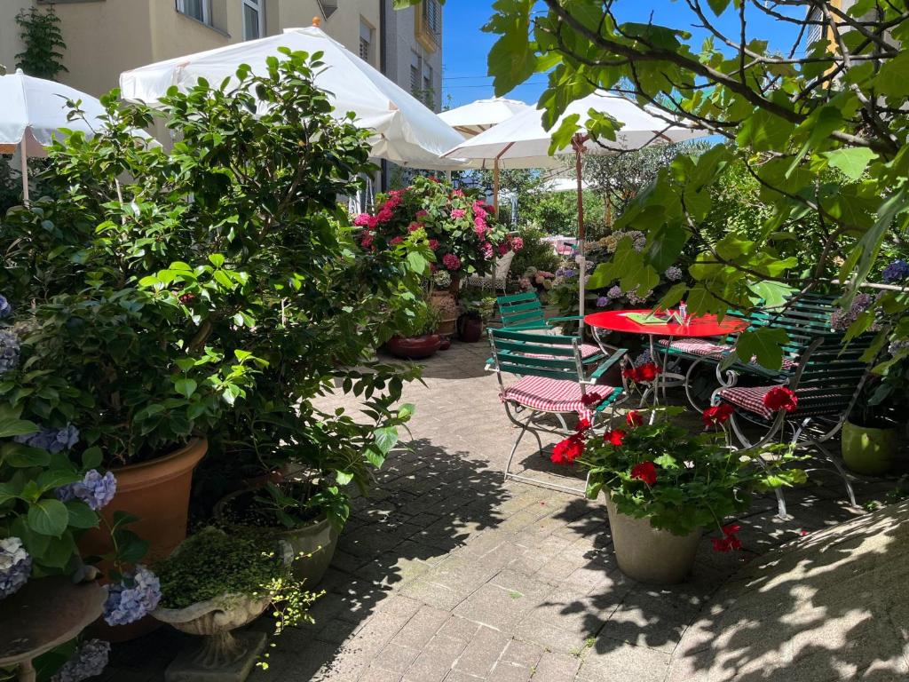 eine Terrasse mit Tischen, Stühlen und Topfpflanzen in der Unterkunft Hotel Mozart in Rorschach