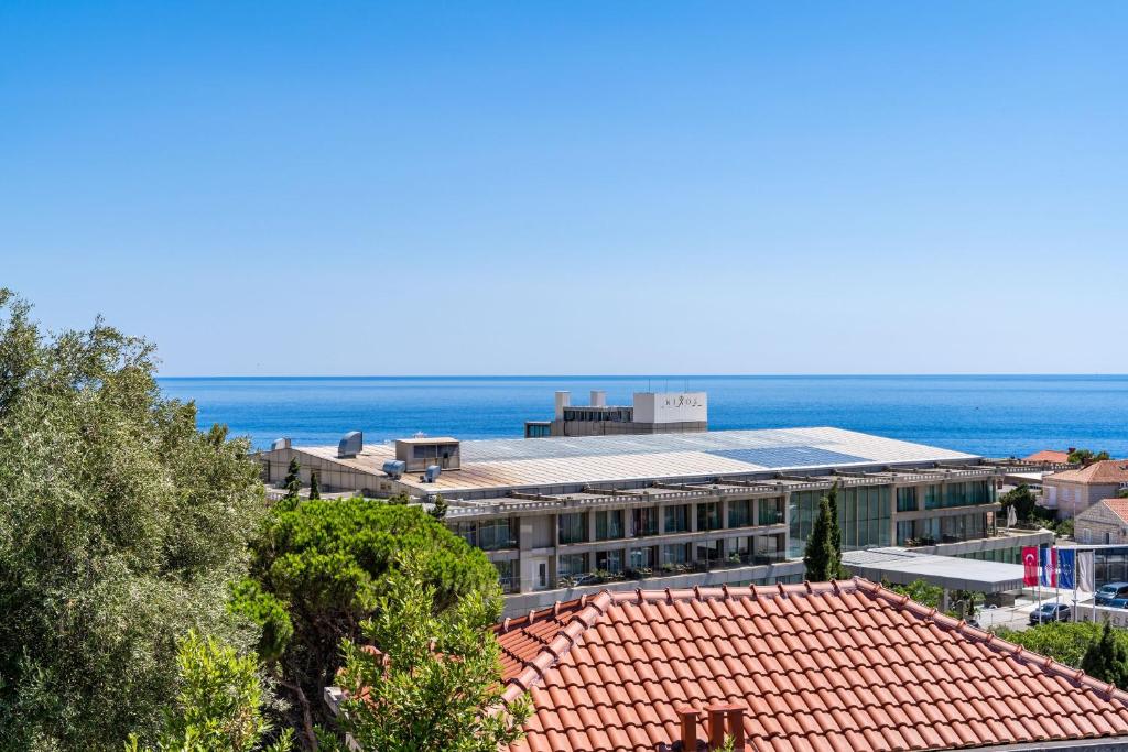 a building with a red roof and the ocean in the background at Rooms Nina in Dubrovnik
