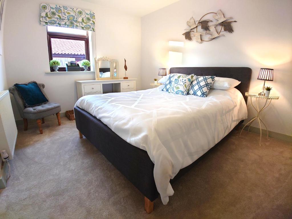 um quarto com uma cama grande e uma cadeira em Avocet Lodge, Snettisham em King's Lynn