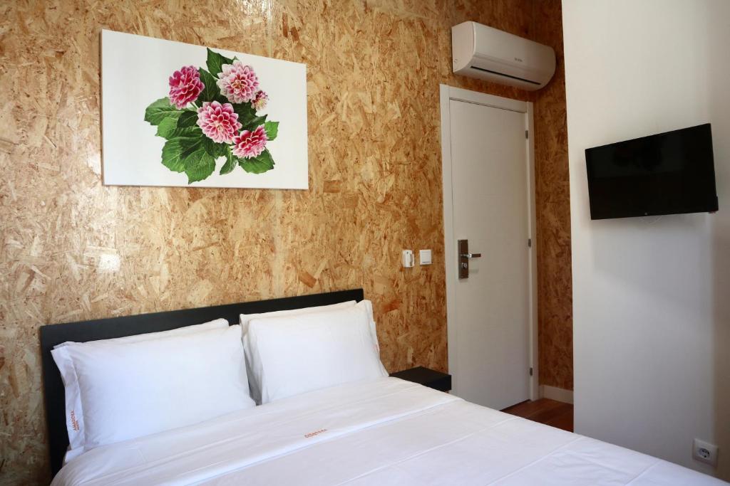 Amadora Boutique Hostel في أمادورا: غرفة نوم بسرير ابيض وتلفزيون