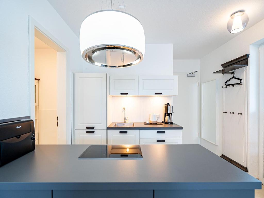 eine Küche mit weißen Schränken und einer großen Leuchte in der Unterkunft Quartier 7, App 06 in Ahlbeck