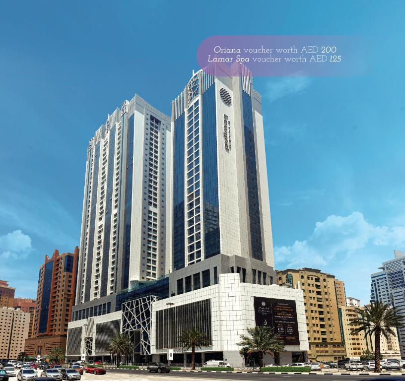 a large building with a clock on it in a city at Pullman Sharjah in Sharjah