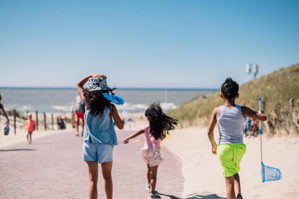 um grupo de crianças caminhando na praia em Stayokay Hostel Noordwijk em Noordwijk
