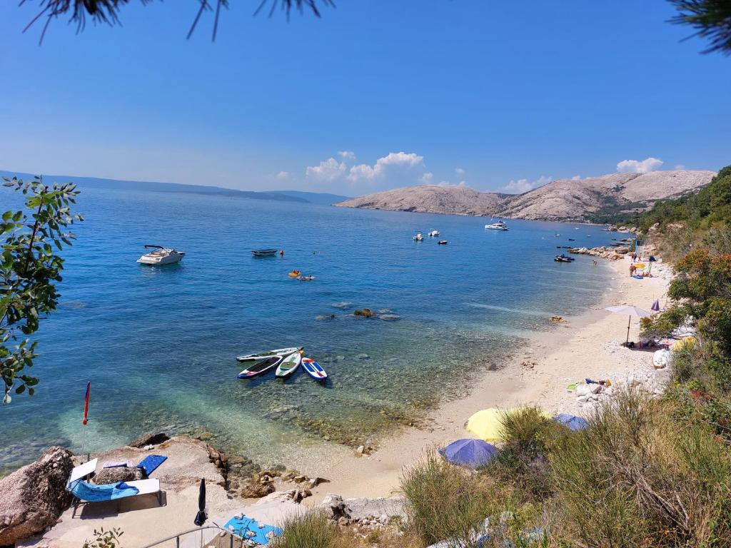 a beach with boats and people in the water at Apartmani Denis in Stara Baška