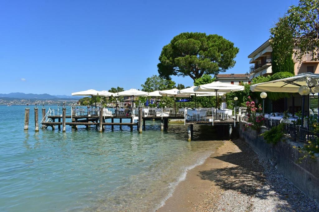 a dock with tables and umbrellas on the water at Hotel Pace in Sirmione