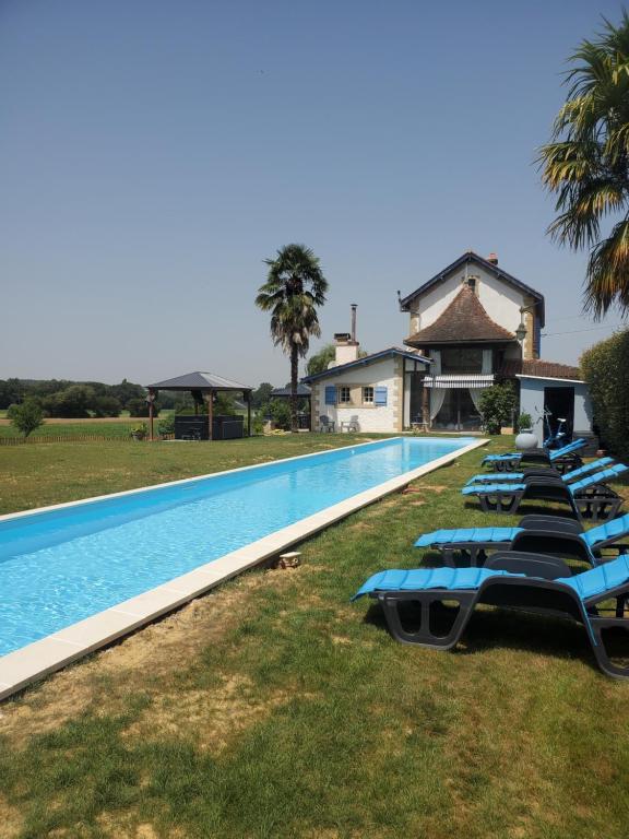 eine Reihe blauer Liegestühle neben einem Pool in der Unterkunft La Gare 