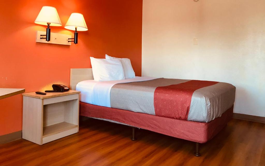 Cama pequeña en habitación con paredes de color naranja en Travelodge by Wyndham Madison Heights MI, en Madison Heights