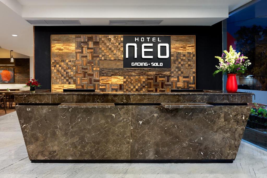 a hotel lobby with a hotel neo sign on a wall at Hotel Neo Gading Solo in Solo