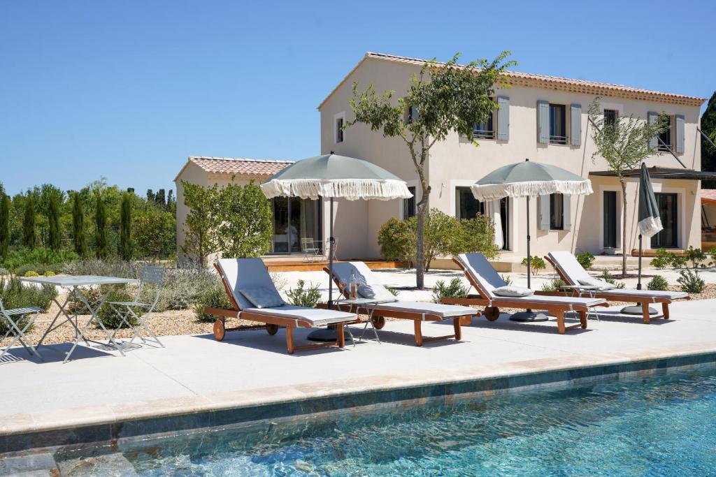 a pool with chairs and umbrellas next to a house at La maison en Provence in Graveson