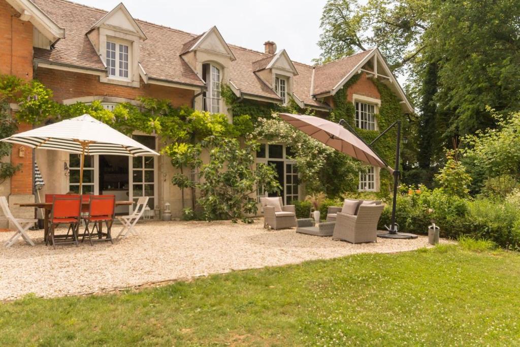 Cette maison dispose d'une terrasse avec des chaises et un parasol. dans l'établissement Manderley, à Arceau