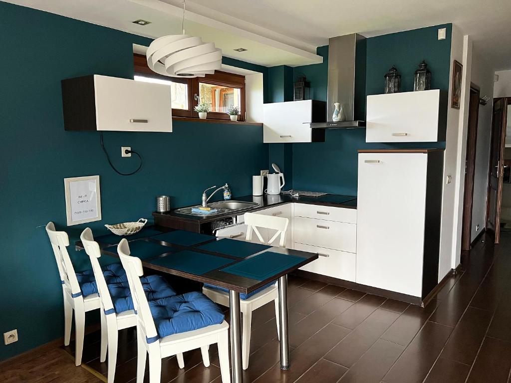 a kitchen with a table and chairs and a blue wall at Apartament M5 Zakopane in Zakopane