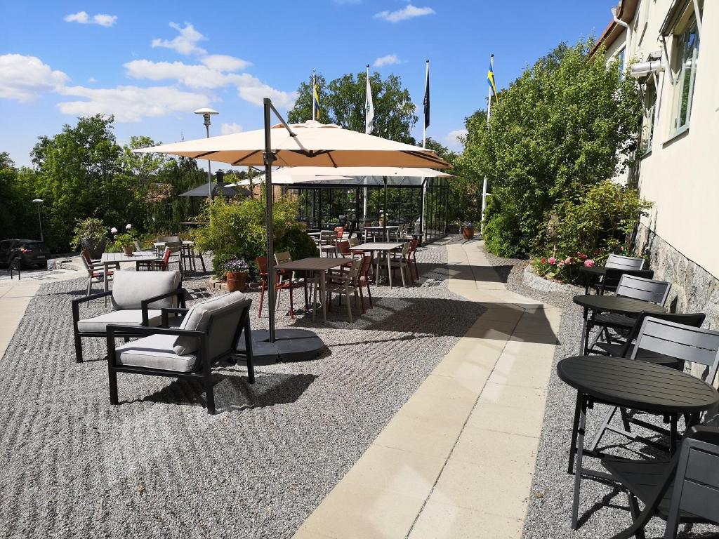 a patio with tables and chairs and an umbrella at Hotell Kristina in Sigtuna