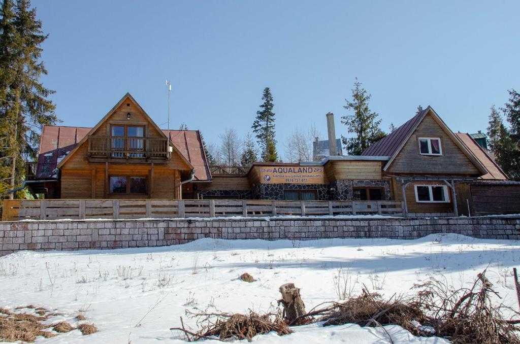 uma grande casa de madeira com neve em frente em Aqualand chata - Športové a výcvikové stredisko ZPS em Dedinky
