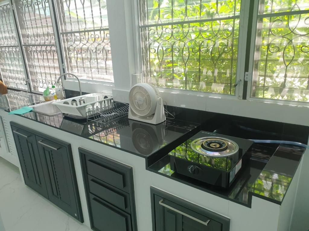 a kitchen with a counter with a fan and windows at Cha-am Beach Vacation Home in Cha Am