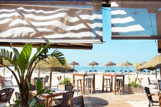 een uitzicht op een strand met tafels, stoelen en parasols bij Piso luminoso cerca de playa in Cádiz