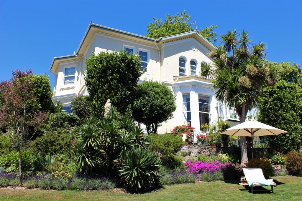 a white house with a garden and an umbrella at Trafalgar House in Torquay