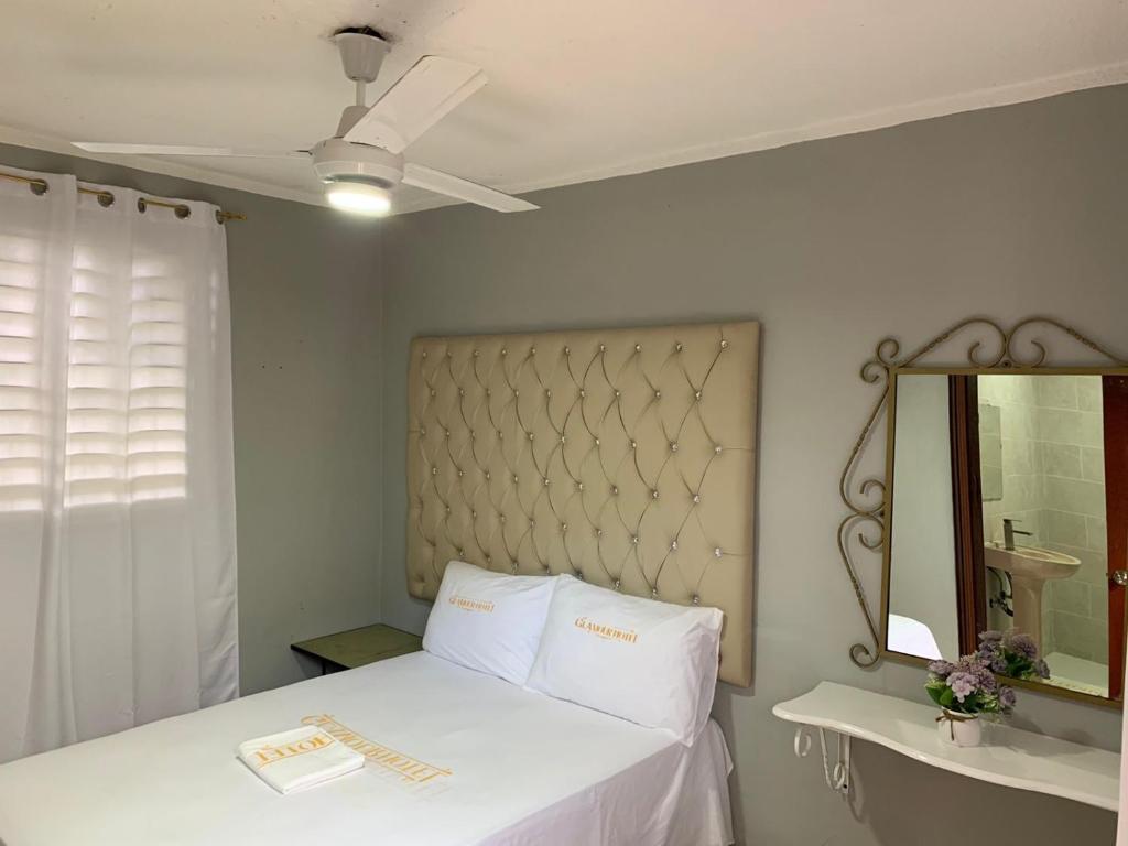 Glamour Hotel في لا رومانا: غرفة نوم بسرير ابيض ومرآة