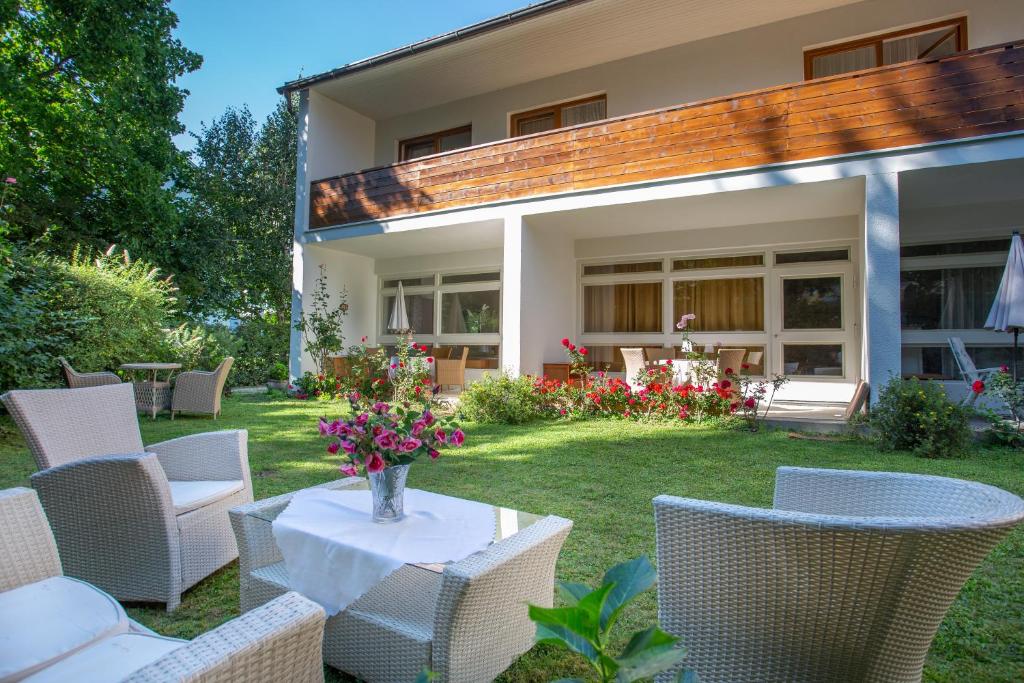 eine Terrasse mit Stühlen und einem Tisch mit einer Blumenvase in der Unterkunft Villa Gabriela in Pörtschach am Wörthersee