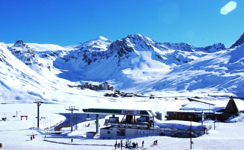 una montaña cubierta de nieve con un lodge de esquí en el primer plano en Hôtel Le Refuge, en Tignes