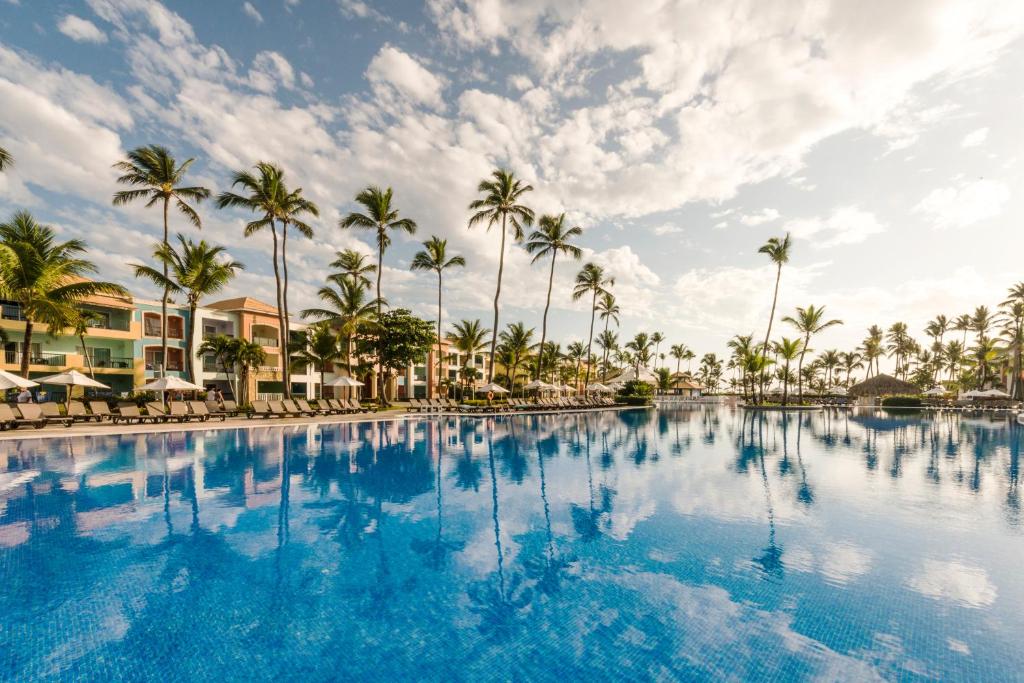 una grande piscina con palme sullo sfondo di Ocean Blue & Sand Beach Resort - All Inclusive a Punta Cana