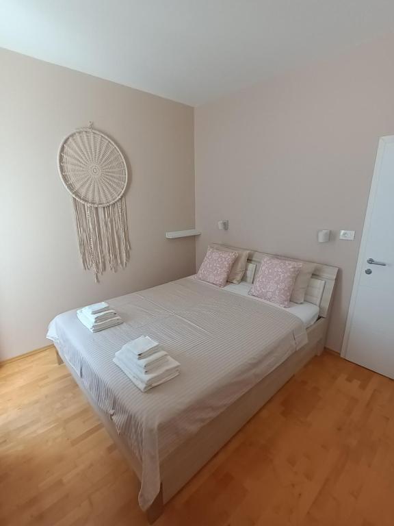 1 dormitorio con 1 cama con sábanas blancas y almohadas rosas en Family Sea Fun Apartment, en Koper