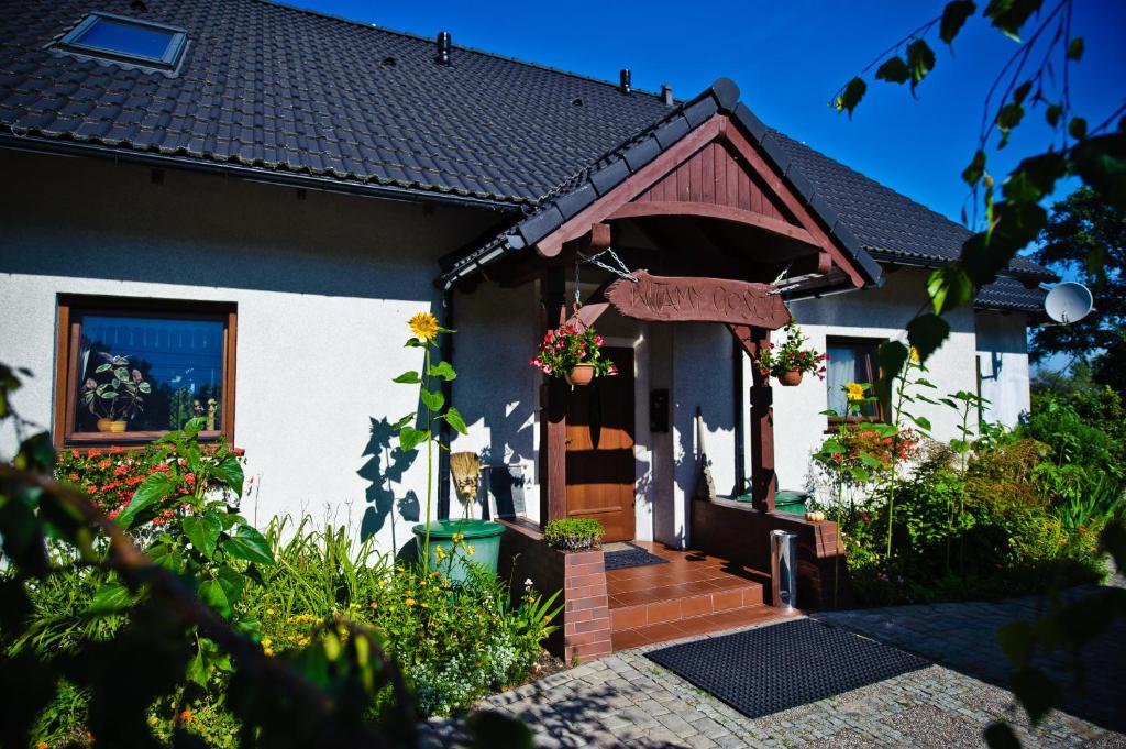 ein Haus mit einer Eingangstür mit Blumen in der Unterkunft Pokoje Gościnne Aga in Widuchowa