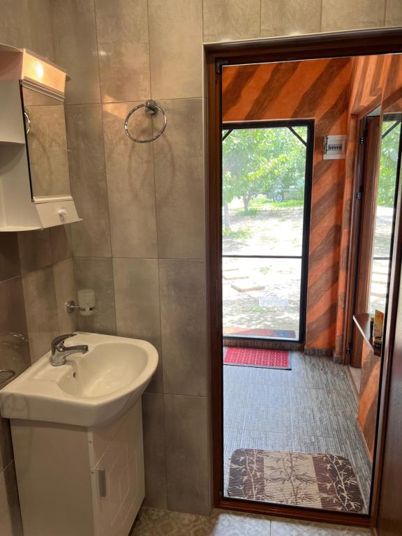 La salle de bains est pourvue d'un lavabo, d'une douche et d'une fenêtre. dans l'établissement Къща за гости Ненийски, à Lom