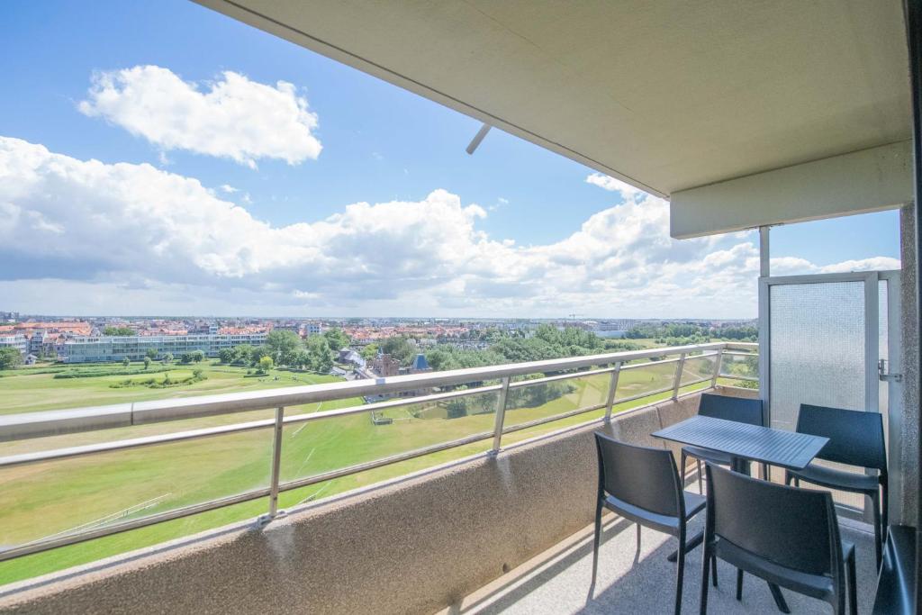 een balkon met een tafel en stoelen en uitzicht op een veld bij Angel by the Waves in Oostende