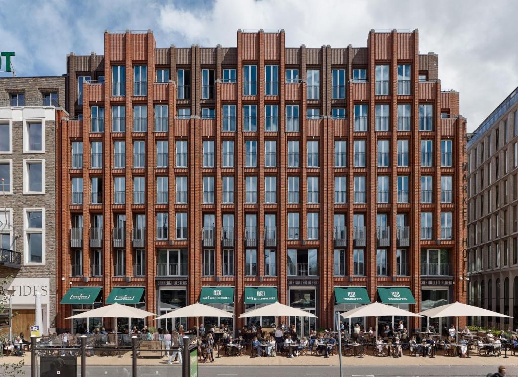 een groot bakstenen gebouw met tafels ervoor bij The Market Hotel in Groningen
