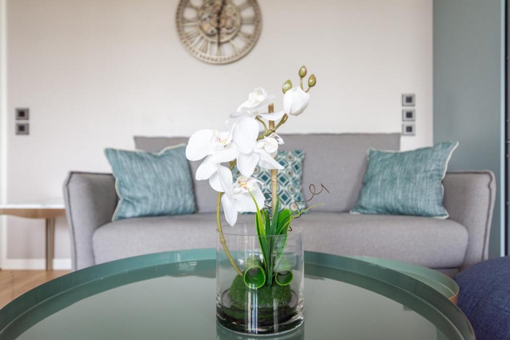 un jarrón de flores sobre una mesa de cristal en la sala de estar en La Dolce Vita By Plaza, en Chessy