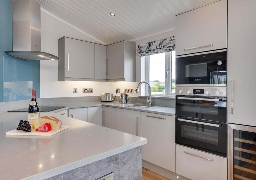 a white kitchen with a bottle of wine on a counter at Briargate 38 in Burnham Market