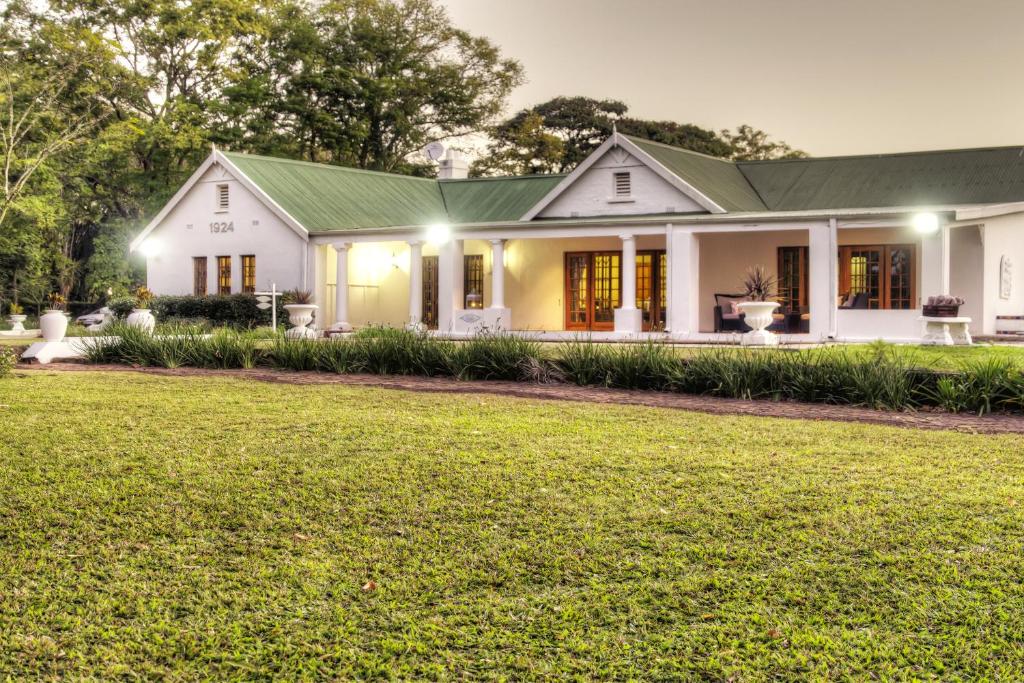 ein weißes Haus mit grünem Dach in der Unterkunft Nut Grove Manor Boutique Hotel in White River