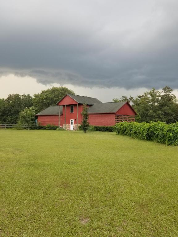 un granero rojo en un campo con un campo verde en Hawks Nest Loft, en Crawfordville