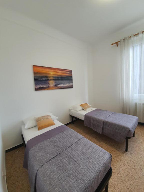 een slaapkamer met 2 bedden en een schilderij aan de muur bij La casa della stazione in La Spezia
