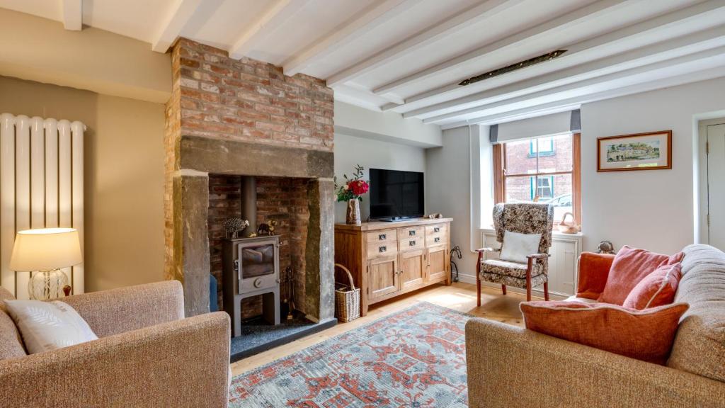 a living room with a fireplace and a tv at Bobbin Cottage in Belper