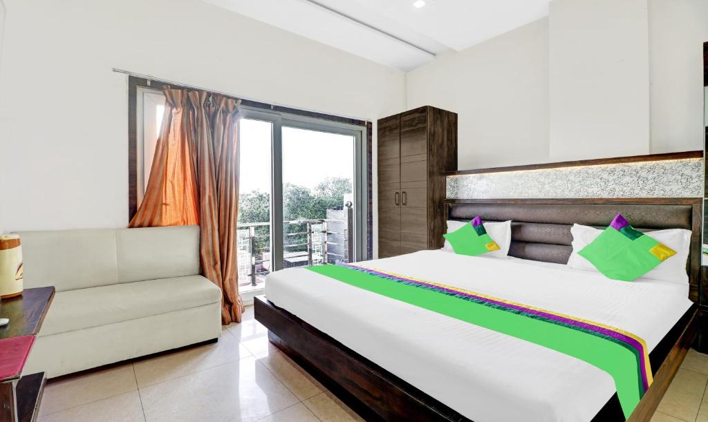 a bedroom with a bed and a couch and a window at Itsy By Treebo - Anjali Mahal 500 Mtrs From Mathura Railway Station in Mathura