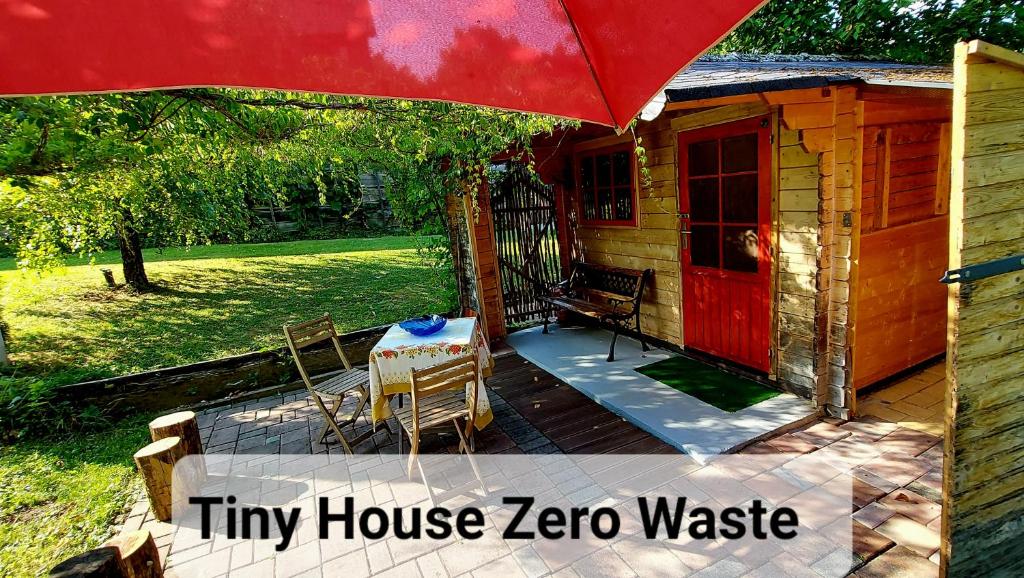 una pequeña casa zoroaza con una mesa y una puerta roja en Natural Cottage Glamping Eco-Tiny House, en Škocjan