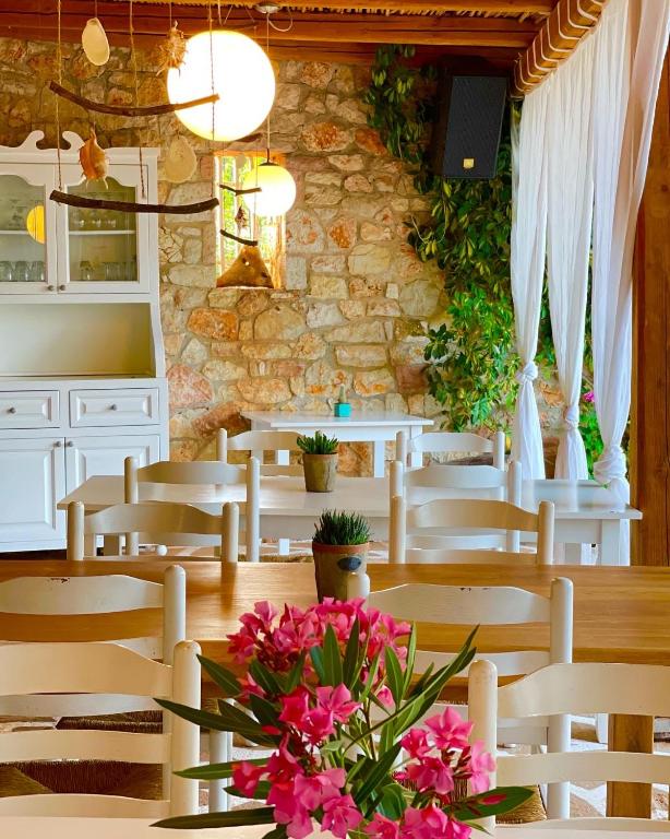 a dining room with white chairs and a table with flowers at Rida Village Ksamil Island in Ksamil