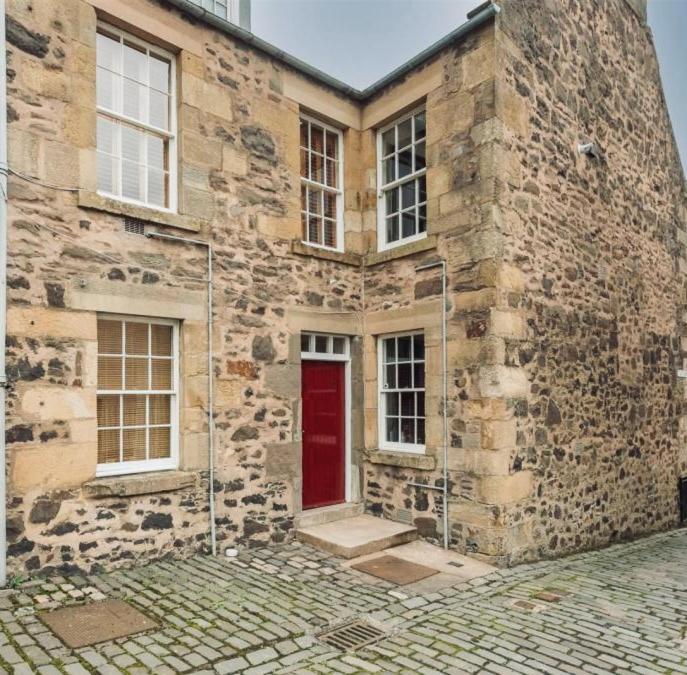 an old stone building with a red door at Towerwell in Newburgh