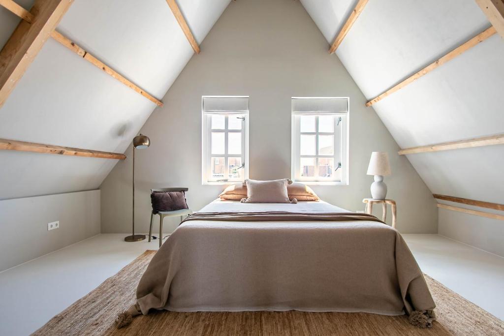 a bedroom with a large bed and two windows at Dok 20, Lemmer in Lemmer