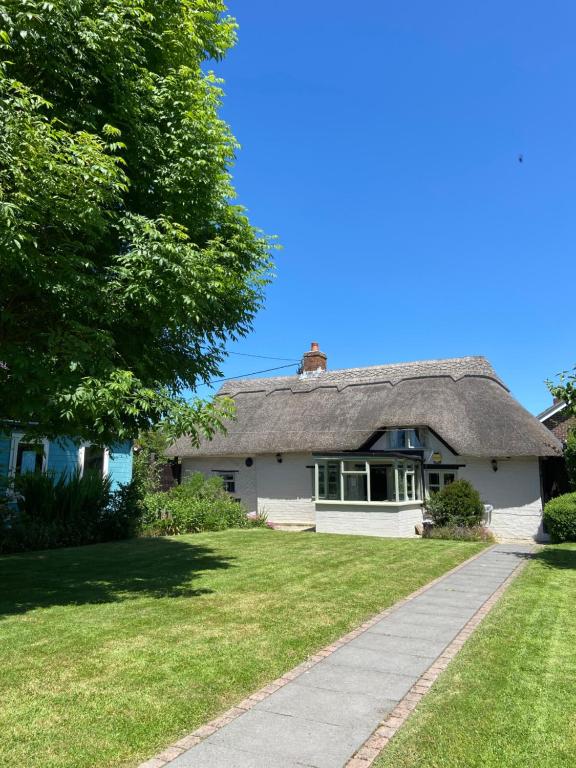 a white house with a thatched roof and a sidewalk at Thatch Cottage, East Boldre nr Beaulieu and Lymington in Brockenhurst