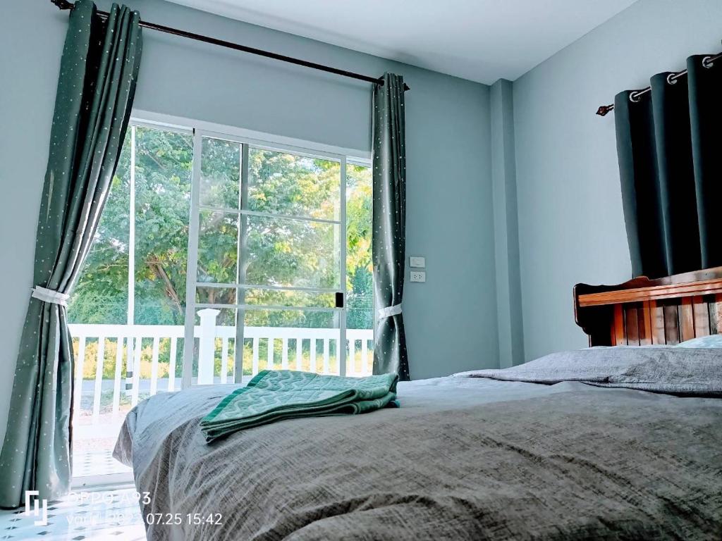 um quarto com uma cama e uma grande janela em บ้านวาริ สะแกกรัง em Uthai Thani