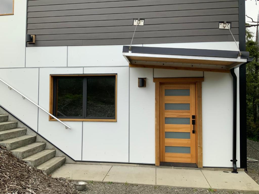 a small white building with a door and stairs at Flo inn in Ucluelet