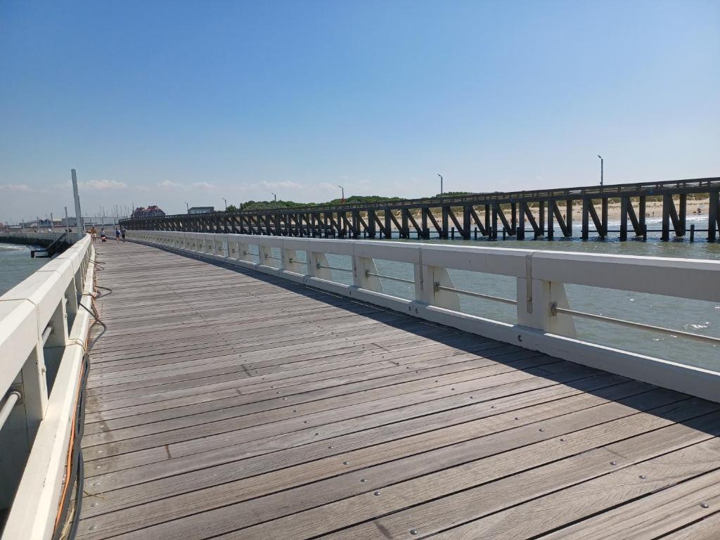 a wooden boardwalk leading to a pier on the water at Appartement Blankenberge Zeedijk aan de Pier in Blankenberge