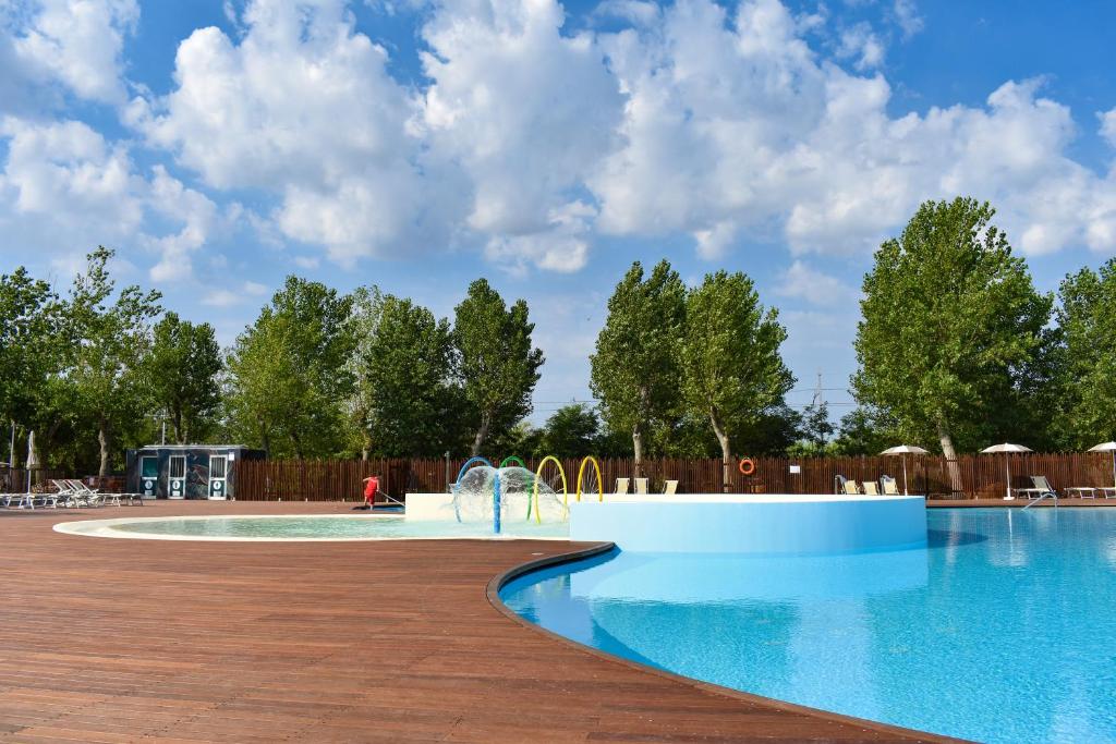 a pool at a resort with a wooden fence at Rimini Family Village in Rimini