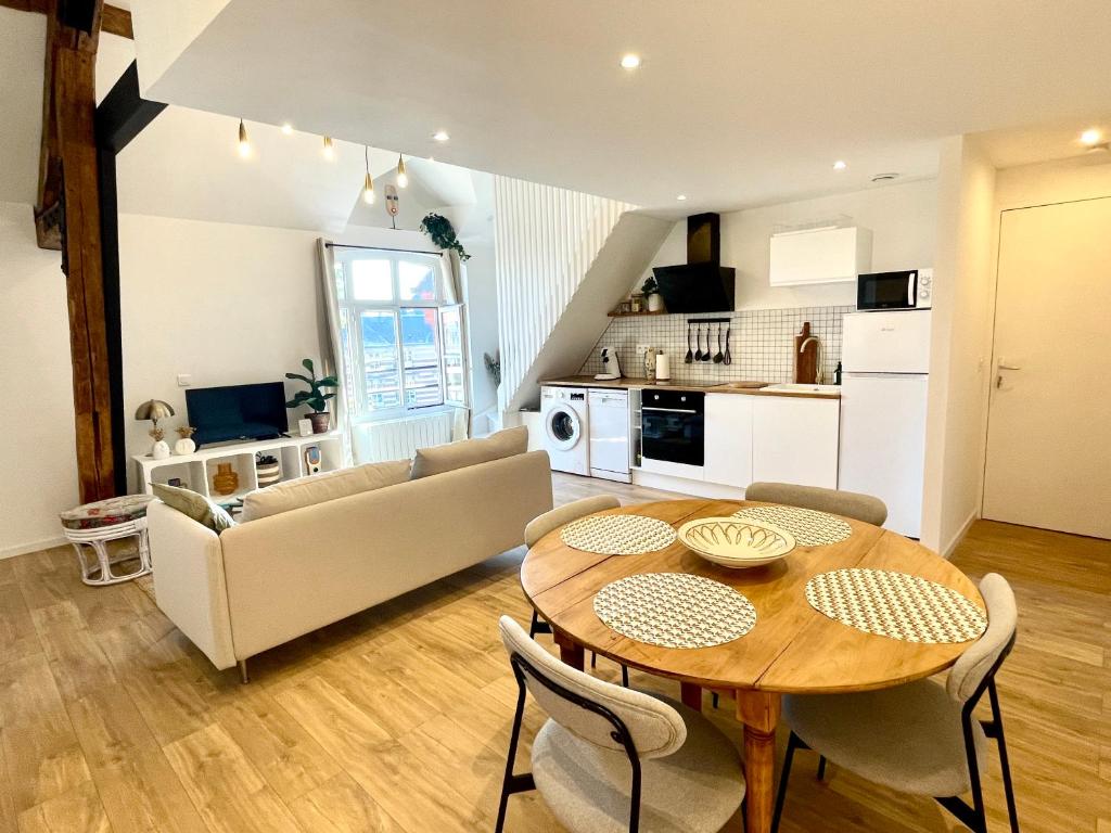 a living room with a table and a kitchen at L'École Buissonnière - Dieppe centre-ville in Dieppe